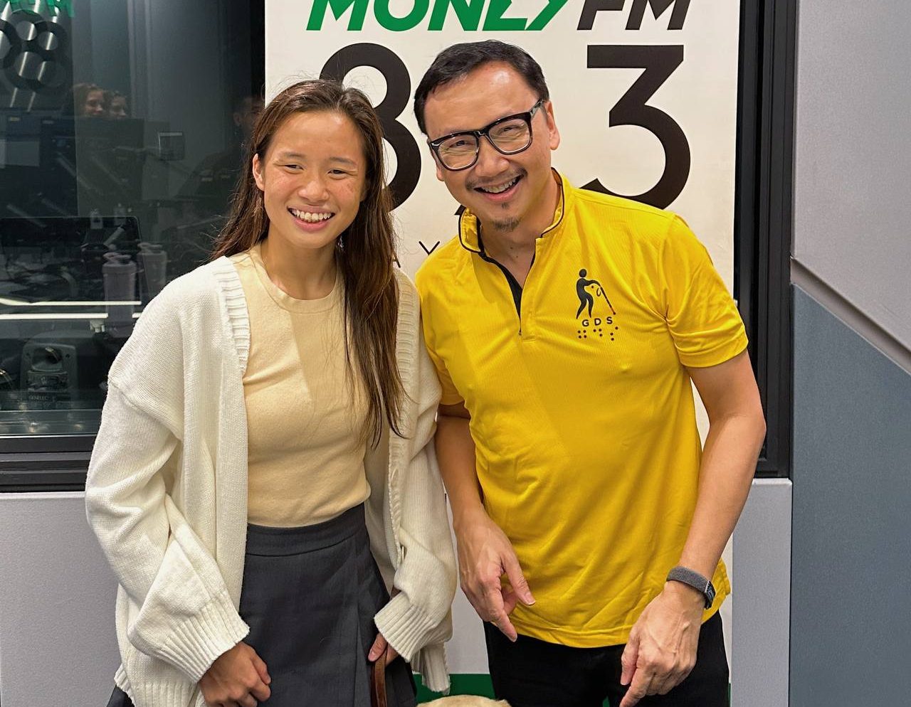 Sophie, her guide dog Orinda and Dr Wong posing together for a group photo in front of 89.3 Money FM banner.