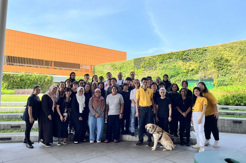 Group photo of NLB staff, GDS staff and guide dog Clare. Everyone is standing close together and posing for the camera
