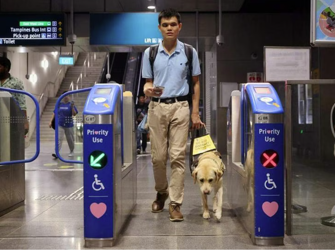 Hong Sen and his guide dog Clare walking through the MRT gantry.