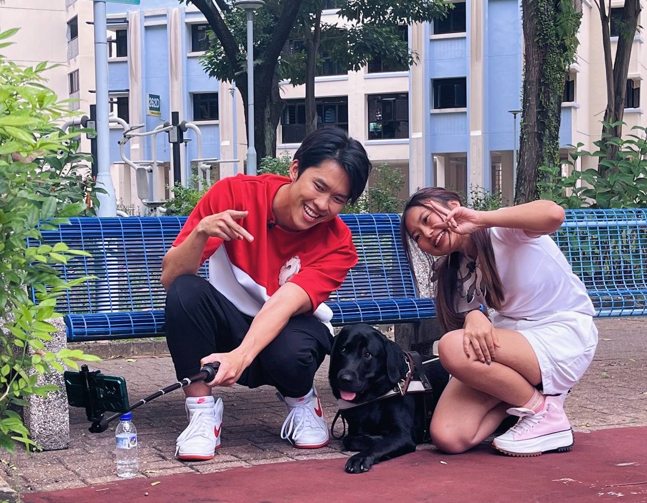Two Curious City hosts posing for a selfie with a black Labrador guide dog.