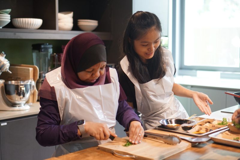 A GDS client and a student volunteer cutting vegetables together.