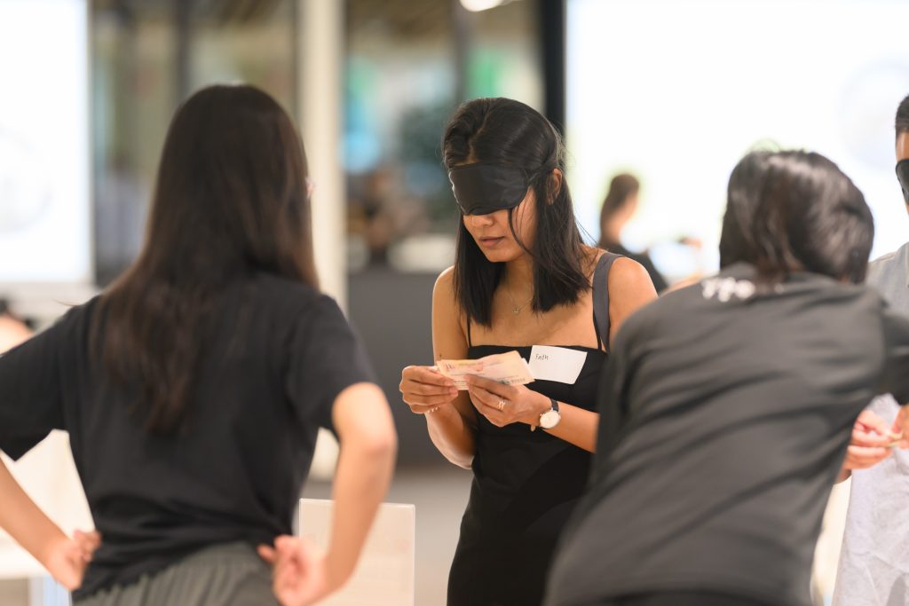 An event attendee sorting notes while wearing goggles that simulate central vision loss. 