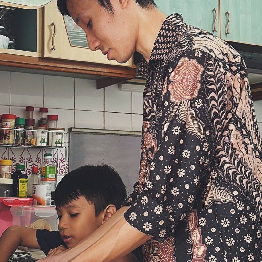 A GDS client and his son washing dishes together in the kitchen.