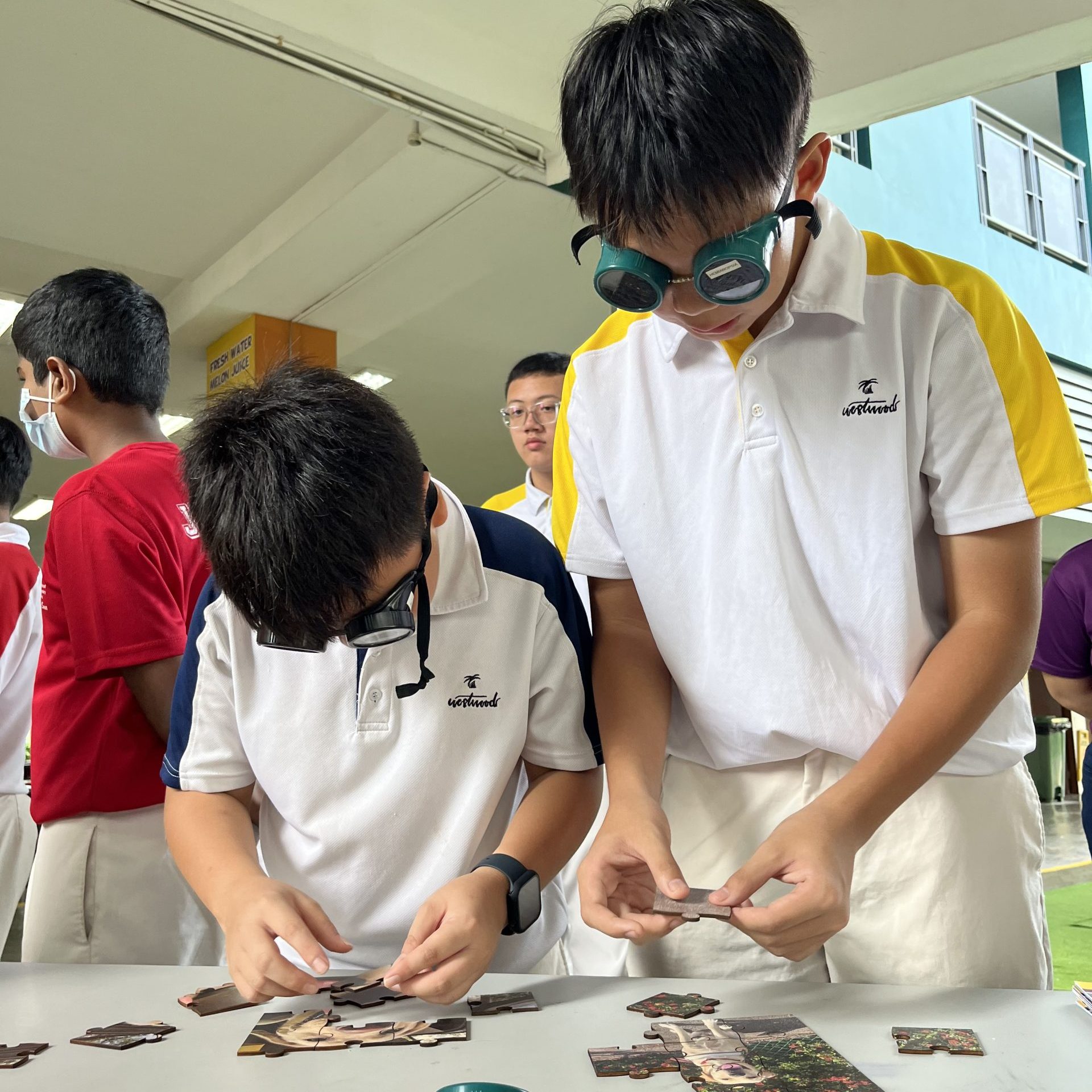 Two Westwood Secondary School students trying on goggles that simulate vision loss, experiencing challenges faced by people who are blind or visually impaired.