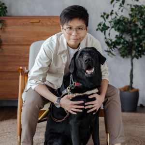 Tan Shi Lin and guide dog Laurie Christina Teng, Guide Dog Mobility Instructor, posing with a black guide dog.